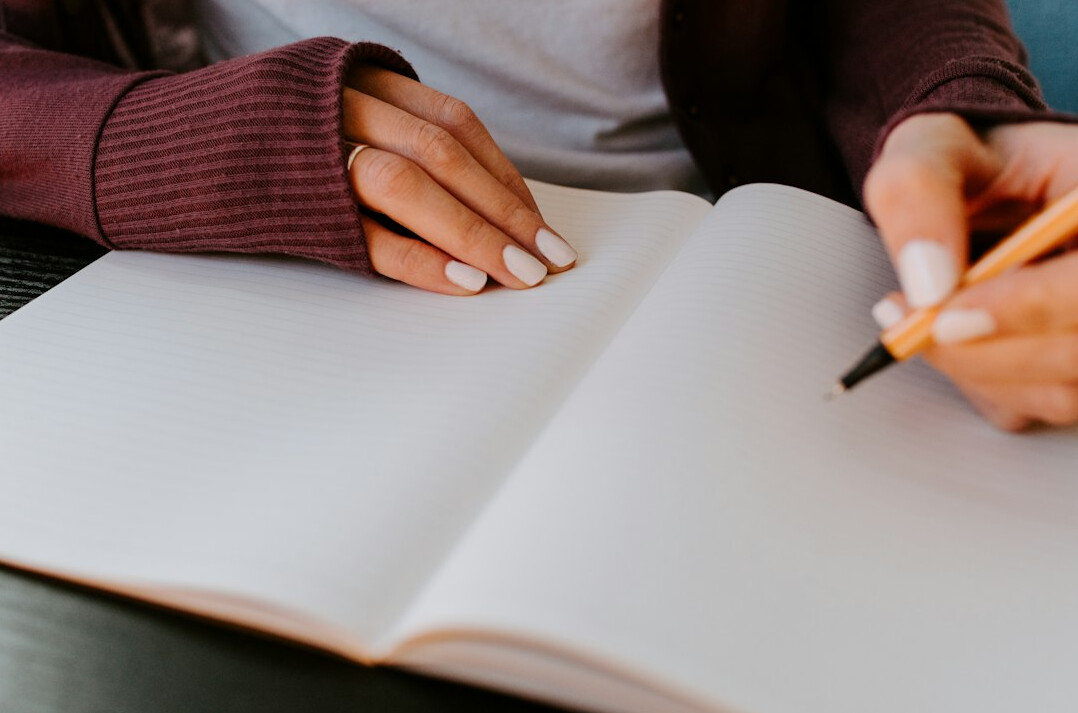 person writing in journal at desk